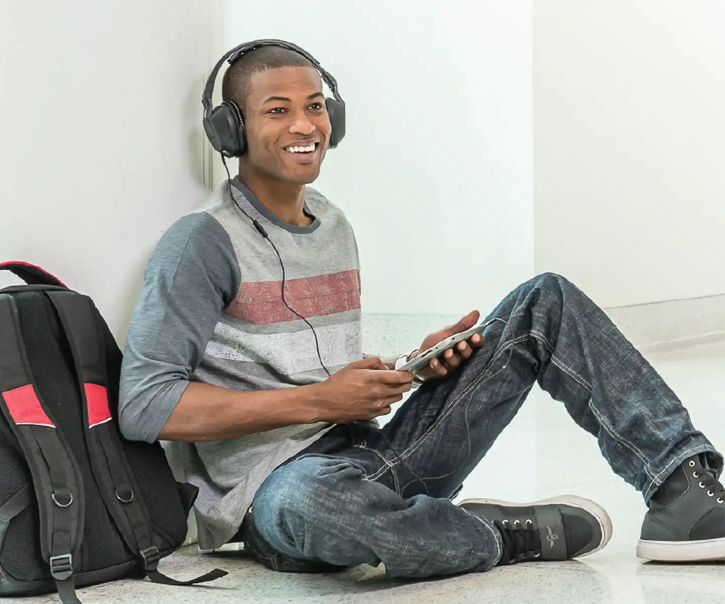 young man seated on floor listening to headphones